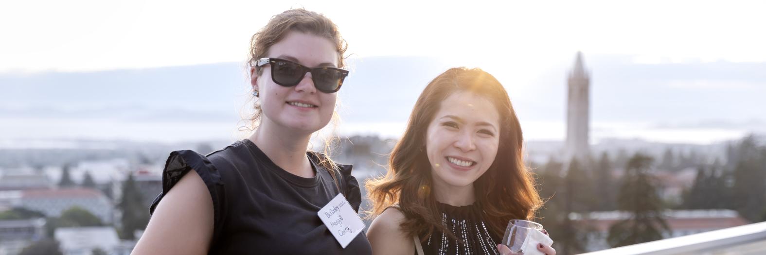 Photo of two MIDS women with the Berkeley skyline and campanile.